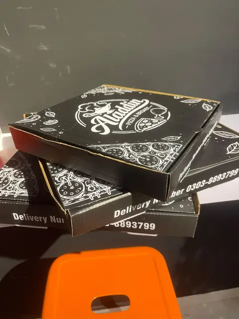 A stack of black Aladdin pizza boxes.