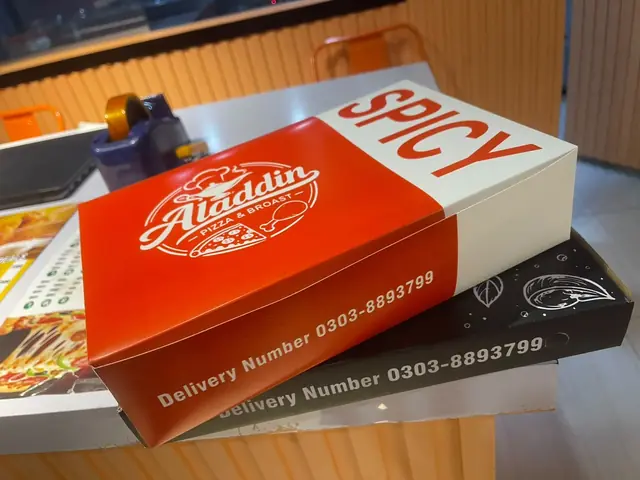 A red spicy box sitting on a black delivery box.
