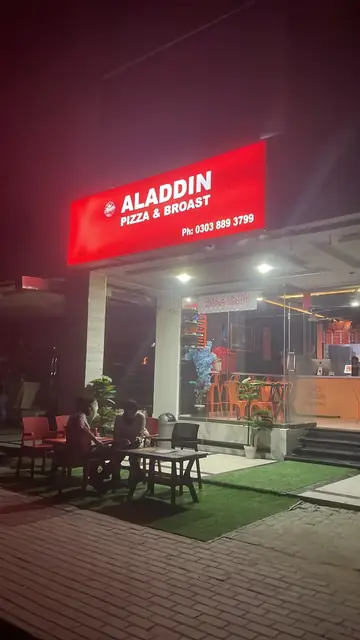 Aladdin Fast Food at night, with the red sign lit and outdoor seating.